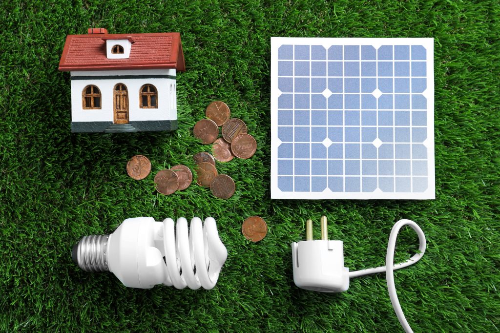 Figurine de maison, economies, ampoule et panneau solaire, representant les economies d'energies