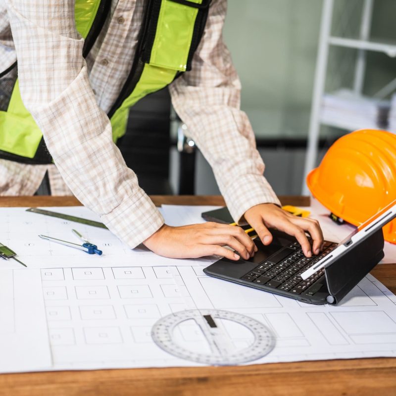 Female architect engineer is drafting blueprints using CAD software, focusing on sustainable infrastructure, renewable energy solutions, and adhering to building codes